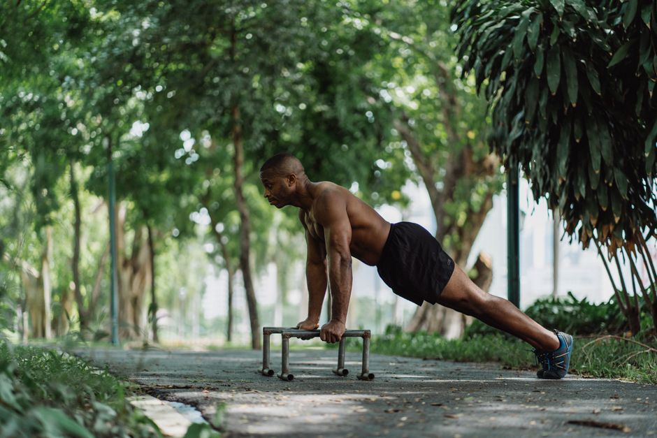 Athletic man doing push-ups in a green park