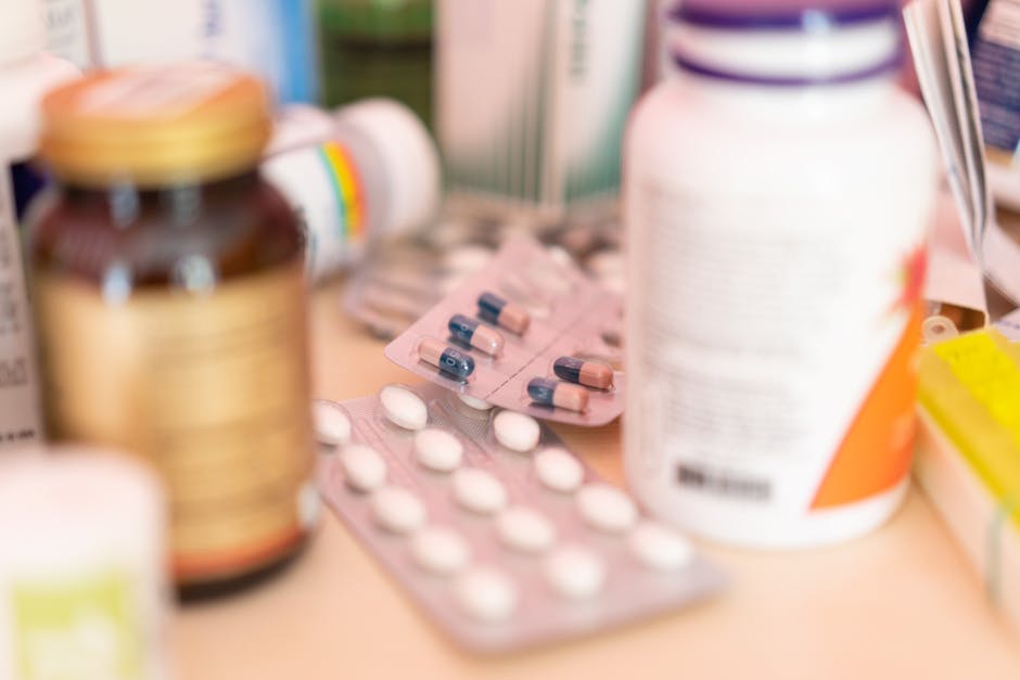 Close-up shot of various pharmaceutical pills, capsules, and medication bottles on a table.