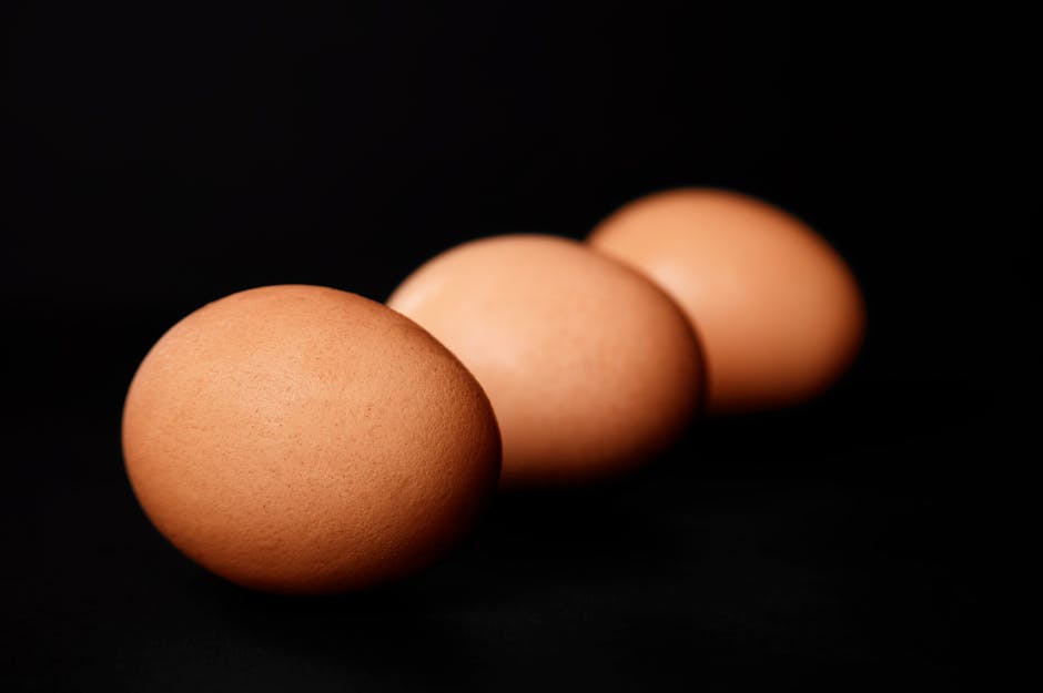 Minimalist still life of three brown eggs on a dark background, highlighting simplicity and natural beauty.
