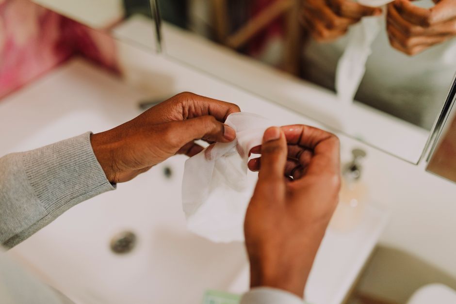 Close-up of hands using a cleansing towel in a serene bathroom setting.