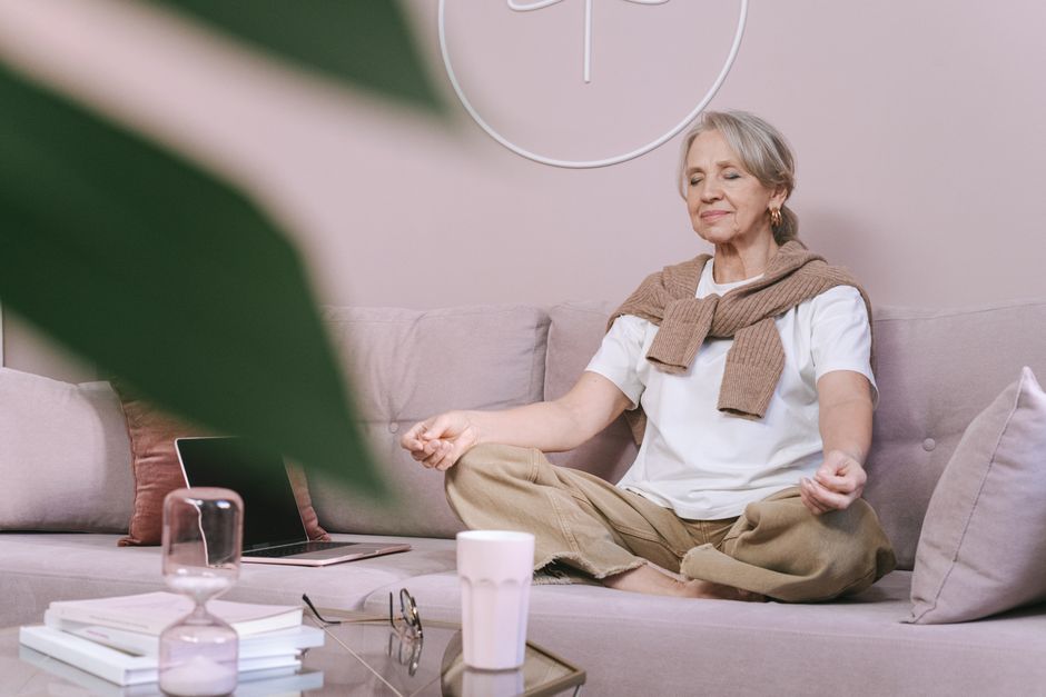 Elderly woman meditating peacefully on a sofa