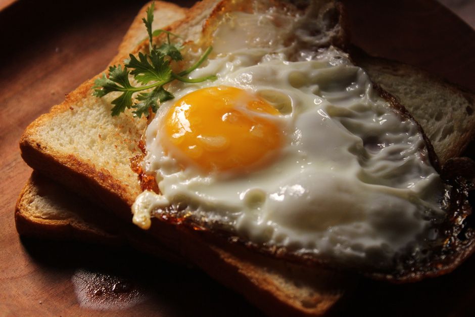 Appetizing sunny side up egg served on golden brown toast with garnish.