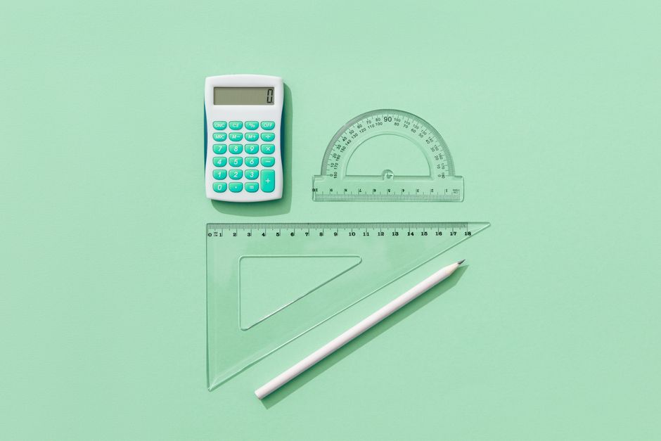 A minimalist flat lay of school supplies on a green background including a calculator, rulers, and pencil.