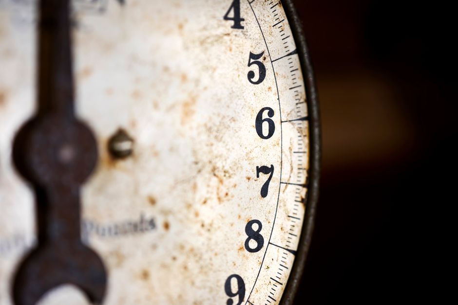 A detailed shot of an old and rusty analog scale with numbers visible.