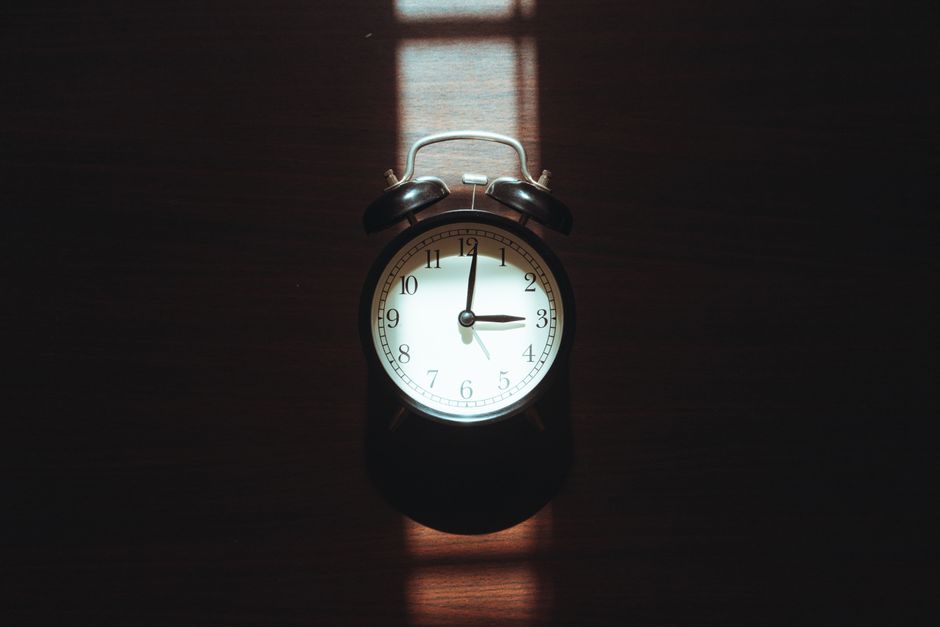 Classic vintage alarm clock with dramatic light and shadow play, evoking nostalgia and warmth.