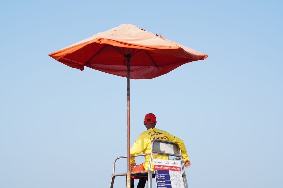 Lifeguard under an orange umbrella at the beach