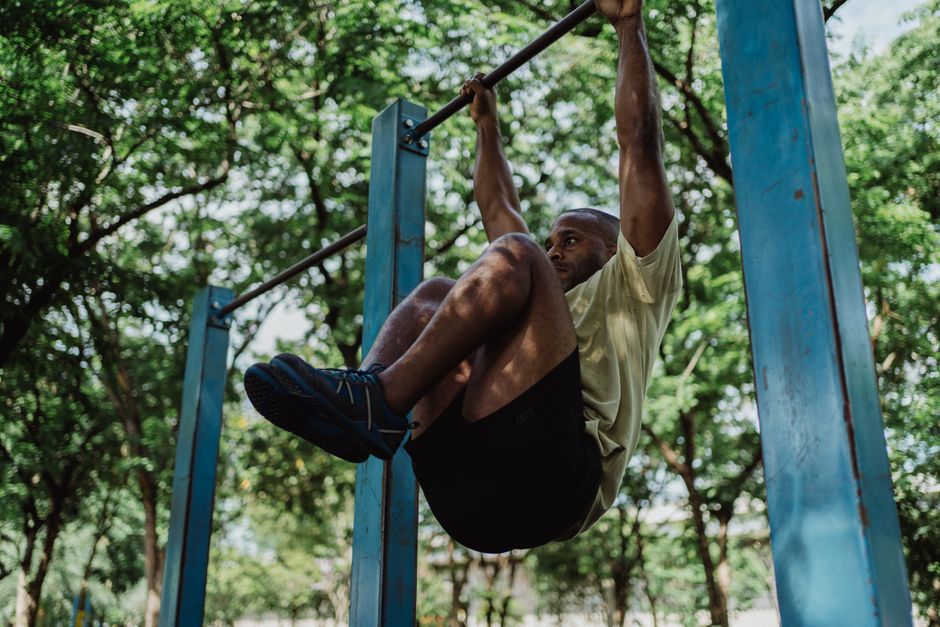 Man doing pull-ups on outdoor bar in a park