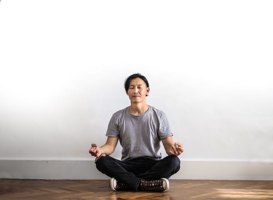 Man meditating indoors on a wooden floor