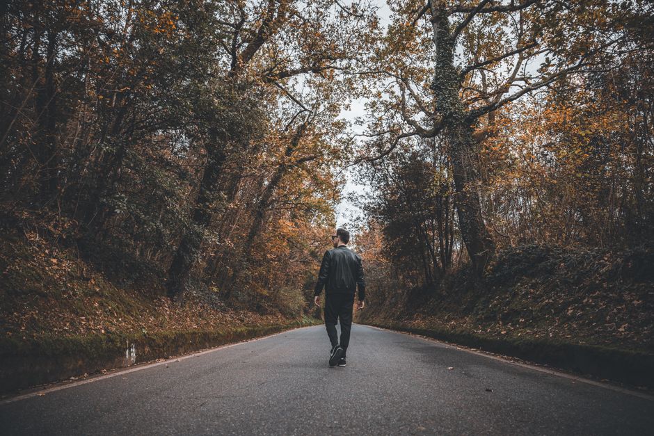 Man walking a peaceful forest road in autumn