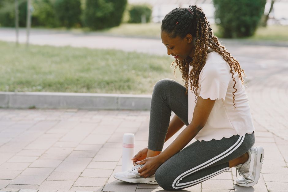 Active outdoor lifestyle with a woman tying her sneakers and relaxing in the park.
