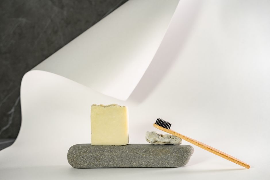 A minimalist arrangement of a soap bar and bamboo toothbrush on a white surface.