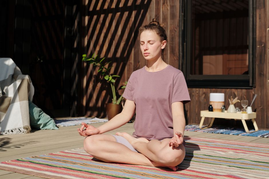 Woman meditating in lotus pose on sunny outdoor deck