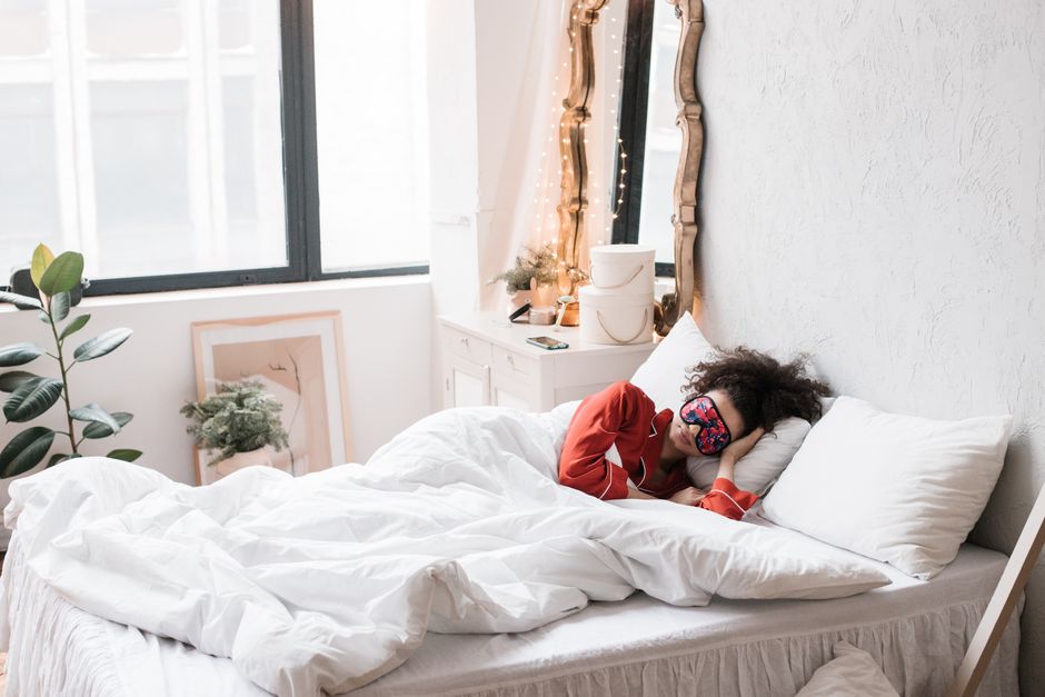 Woman resting with sleep mask on a cozy bed